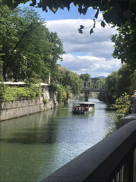 Een foto van de Ljubljanica met in de verte een excursieboot en de schoenmakersbrug