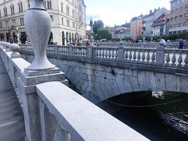 Een foto van de Drie Bruggen met een blik op het water van de Ljubljanica