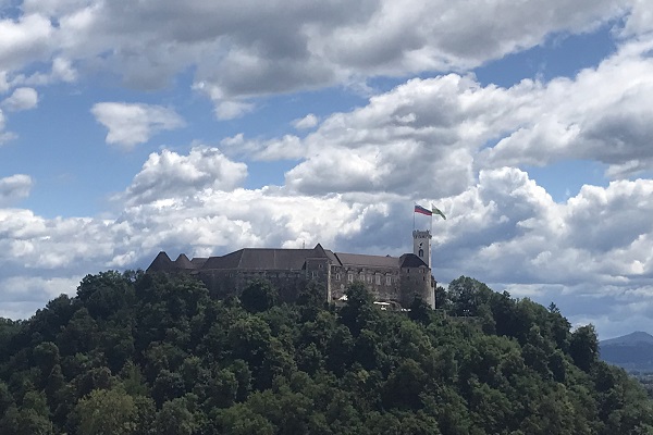 Een uitzicht op het kasteel van Ljubljana met de Sloveense vlag en de vlag van Ljubljana op de toren