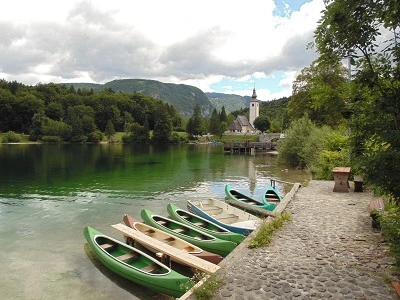 Foto van meer van Bohinj met op de voorgrond groene kajakken